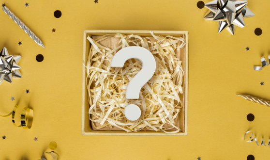 Large question mark inside a box surrounded by party supplies