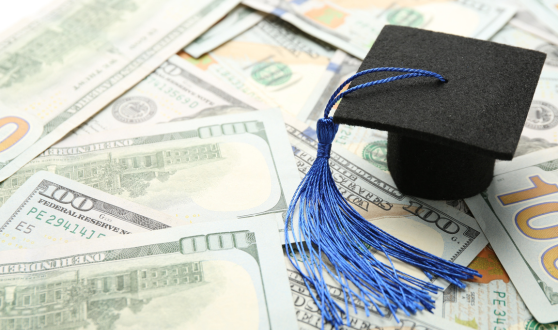 Tiny graduation cap on a group of hundred-dollar bills