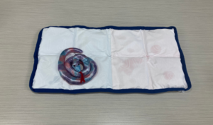 Shiny purple pink and blue stuffed snake toy on top of blue and white weighted pad